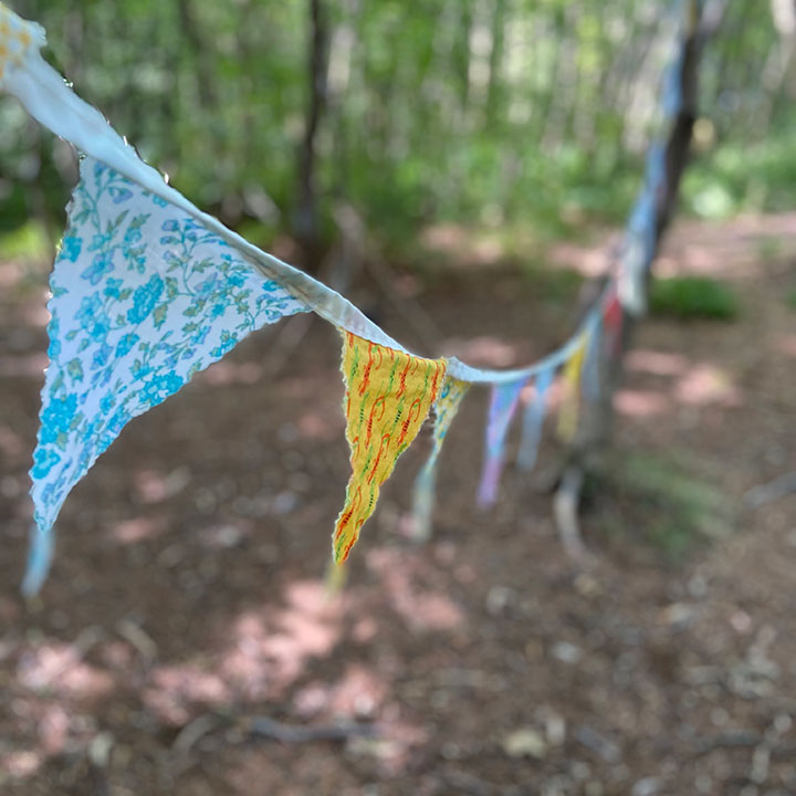 Colourful handmade flag bunting hanging in the trees