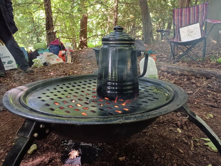 The coffee pot is sitting on the fire pit